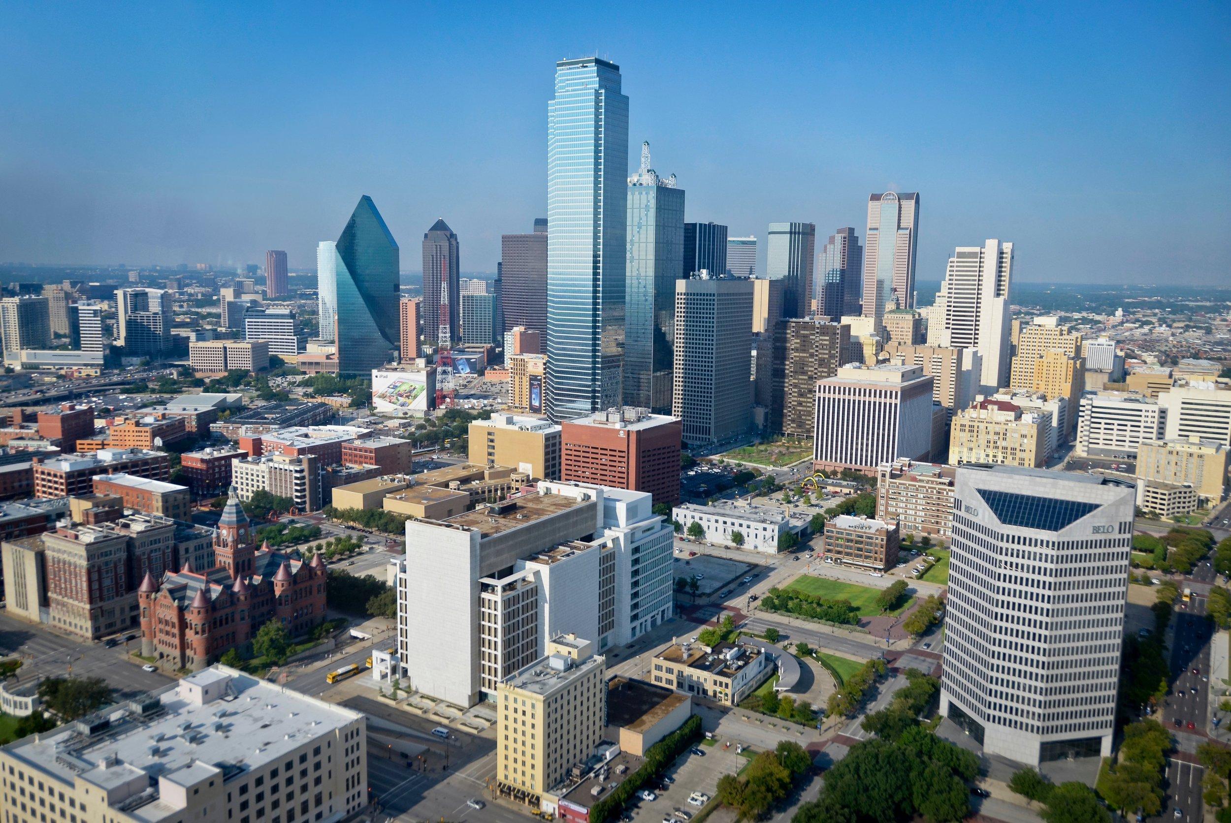 Aerial view of downtown Dallas skyline featuring iconic buildings including Bank of America Plaza and Fountain Place on a clear day