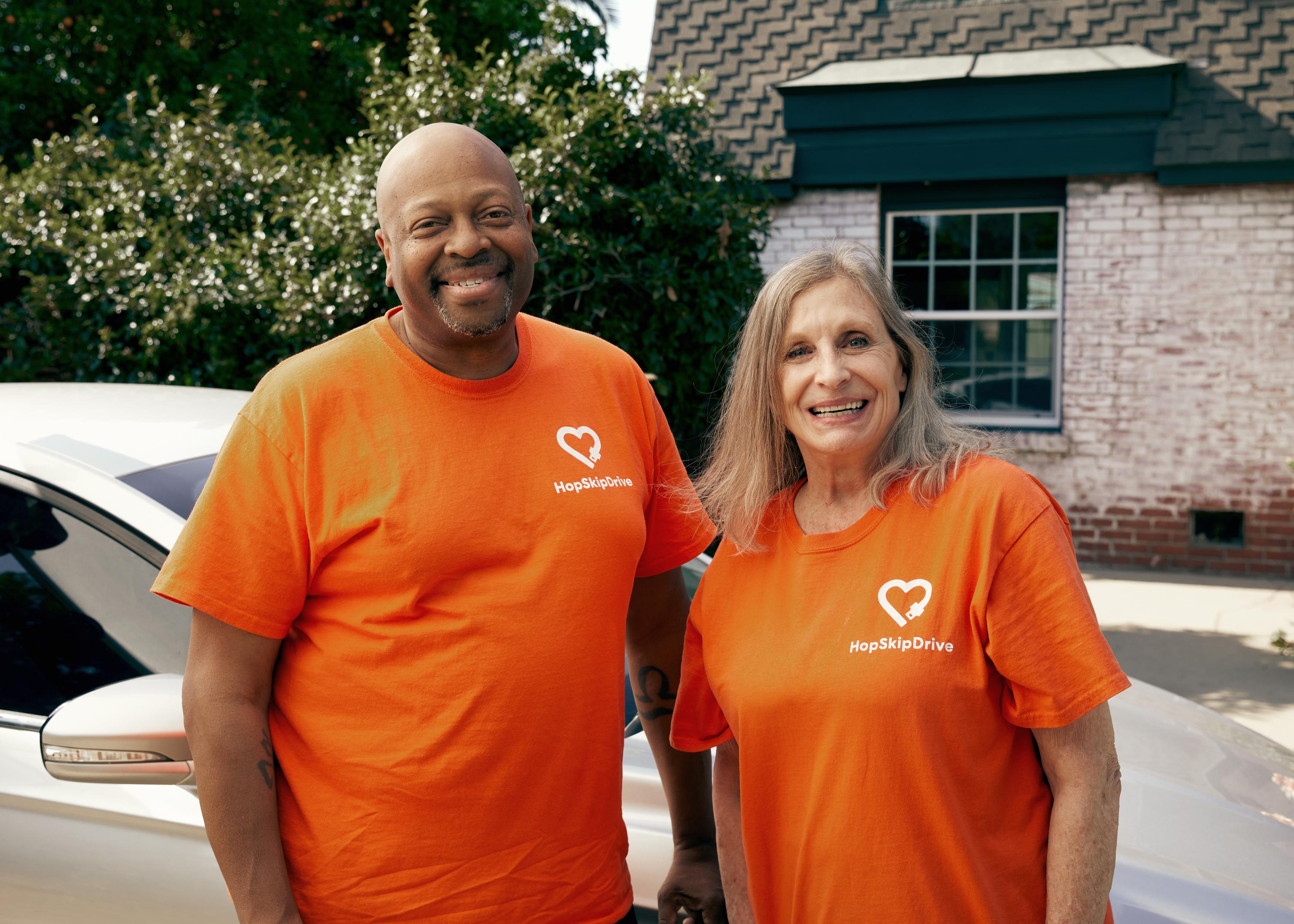 Two HopSkipDrive CareDrivers stand in front of a small vehicle.