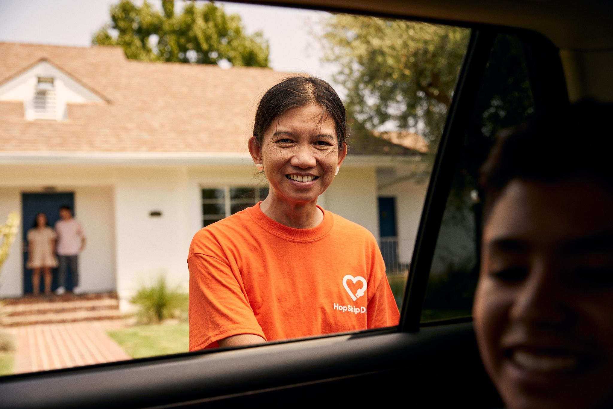 HopSkipDrive CareDriver closing car door for rider while parents look on.