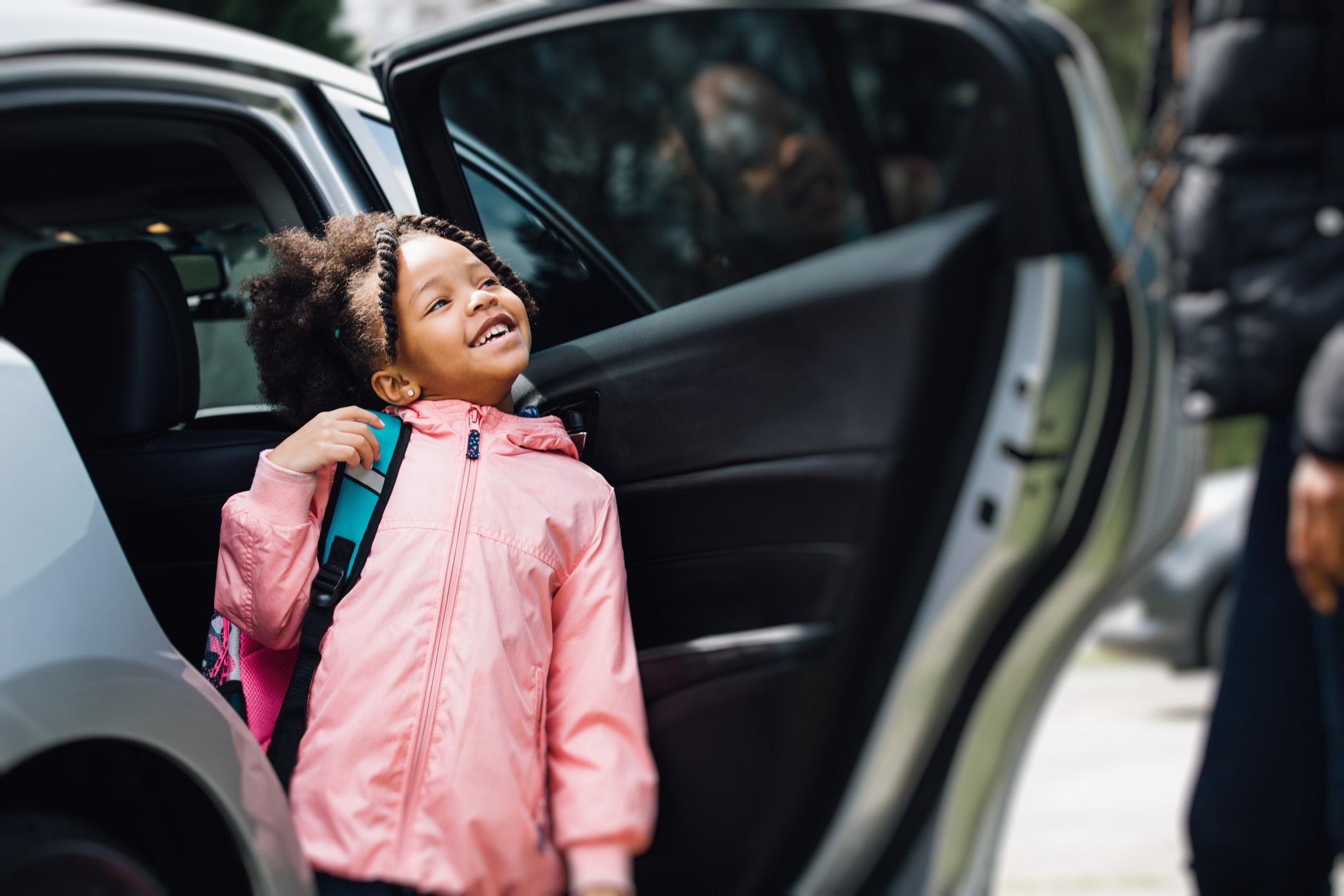 A student exits a small vehicle on her way to school.