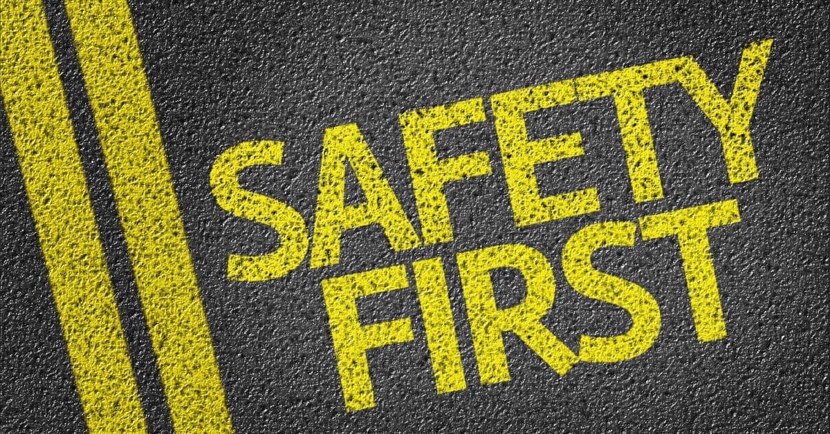 Yellow text reading 'SAFETY FIRST' stenciled on dark asphalt with textured surface