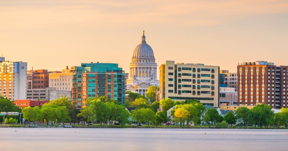 Madison Wisconsin skyline with State Capitol dome rising above modern buildings along Lake Monona at sunset