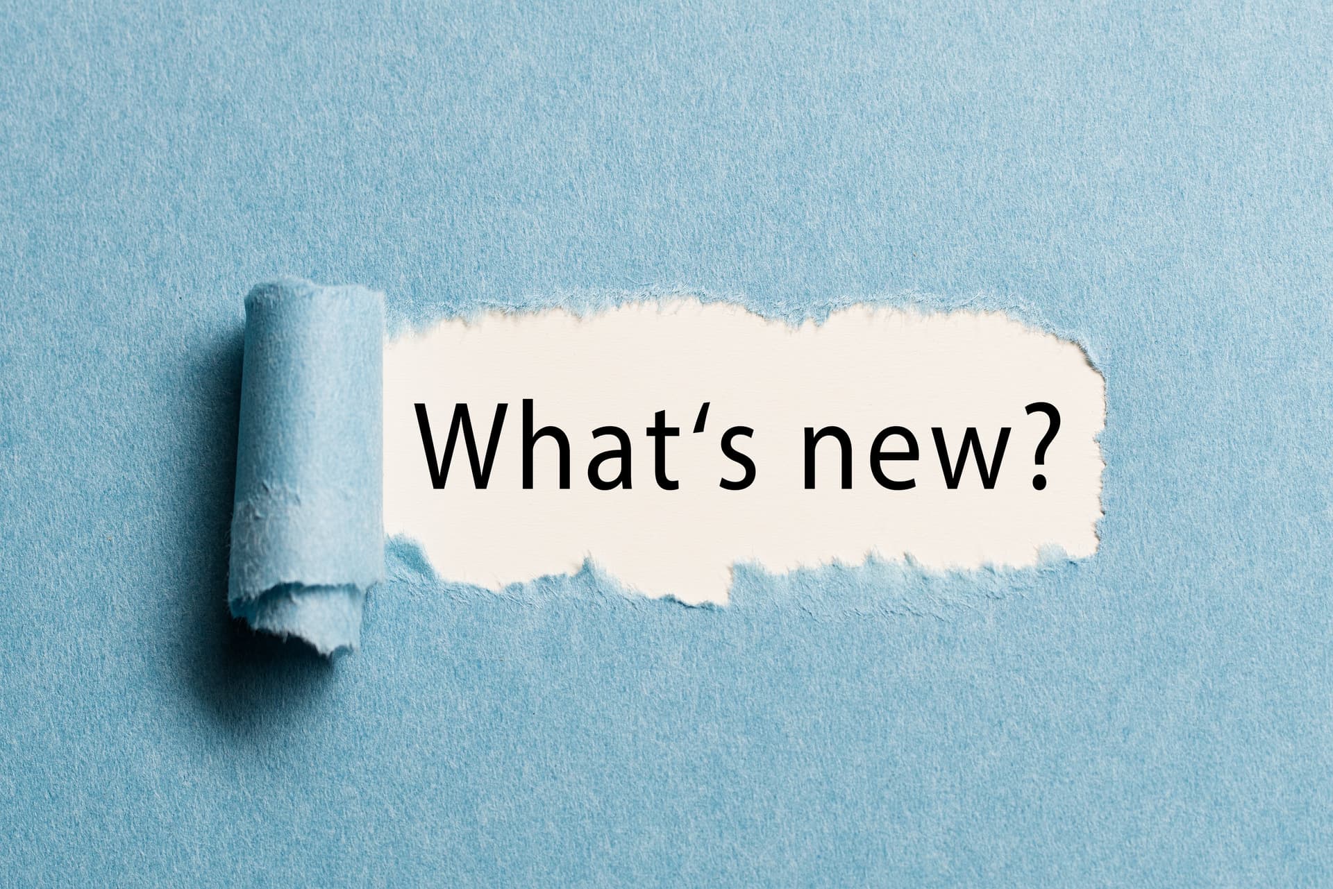 Text reading 'What's new?' revealed under torn blue paper