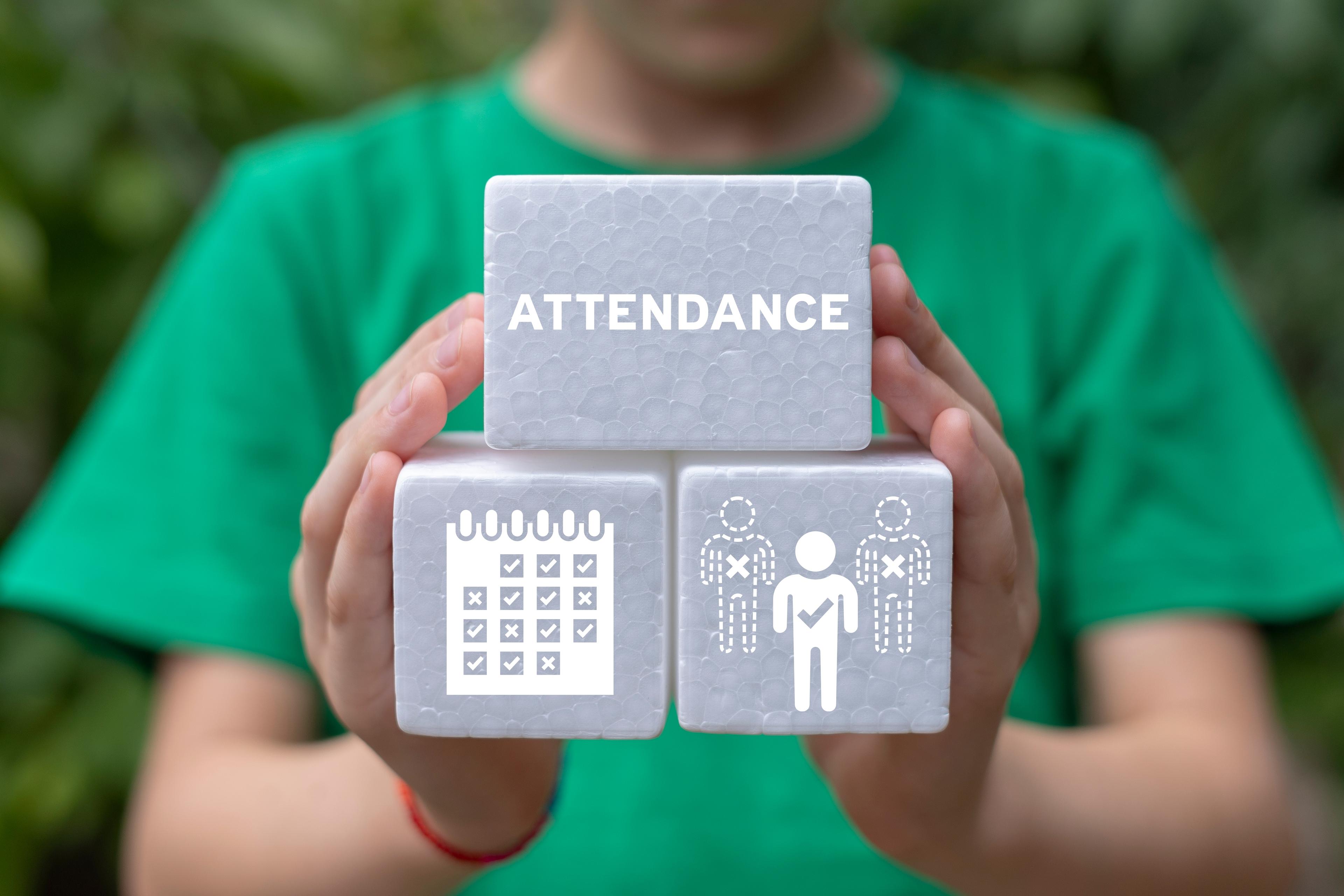Hands holding three silver blocks showing attendance concept with calendar and people icons, and 'ATTENDANCE' text