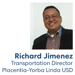 Professional headshot of a smiling person in business casual attire with glasses against a light background